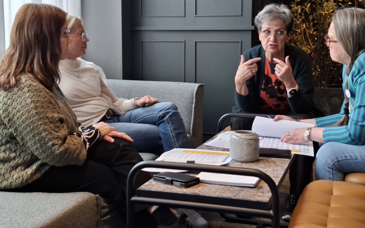 Fyra personer sitter vid ett bord och diskuterar