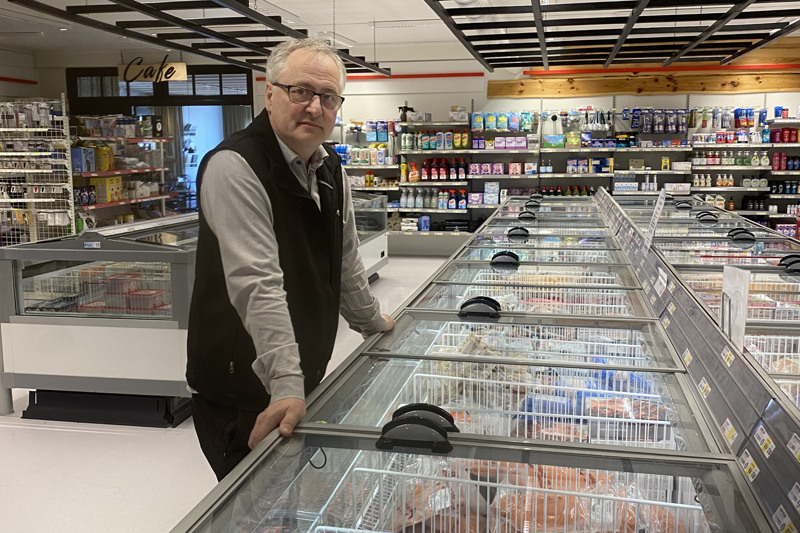 Man står lutad mot en frysdisk i en mataffär.