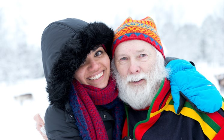 Glad kvinna håller armen om man i samisk klädsel