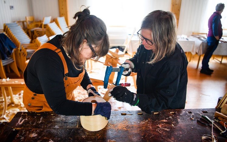 Två kvinnor arbetar med trä på en snickarbänk