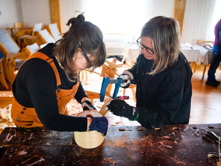 Två kvinnor arbetar med trä på en snickarbänk