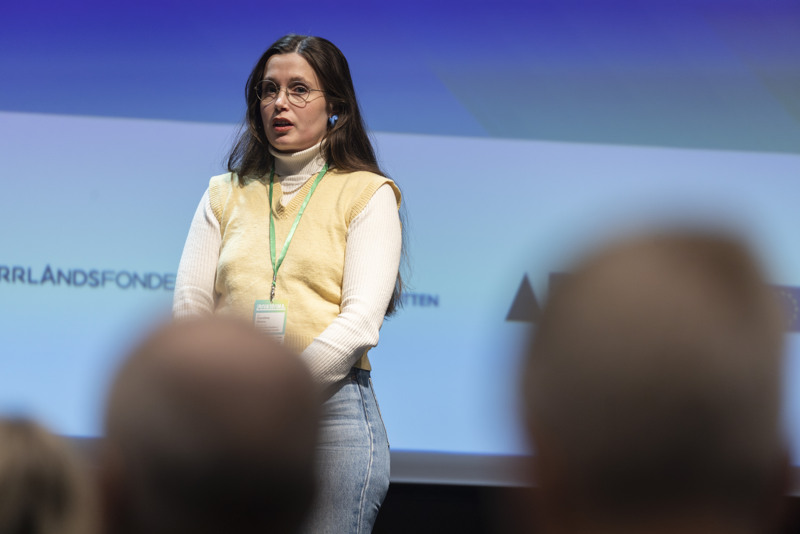 Carolina Lundmark Weinz står på scen och talar på en konferens.