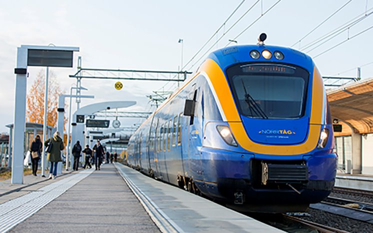 Blått Norrtåg står vid järnvägsstation.