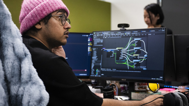 Man i rosa mössa sitter framför en datorskärm