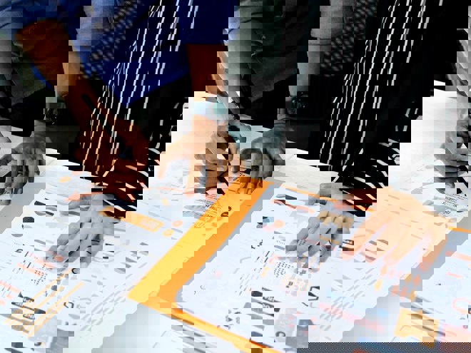 Person analyserar pappersdiagram på skrivbordet.