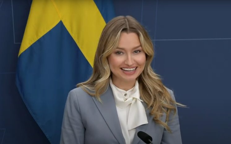 Näringsminister Ebba Busch talar på ett podium framför en svensk flagga.