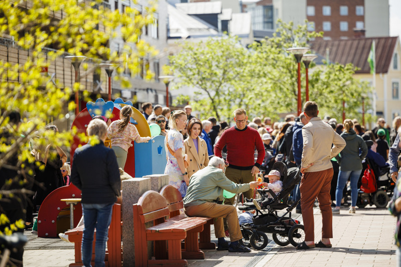 Folkvimmel i stadsmiljö en solig sommardag.