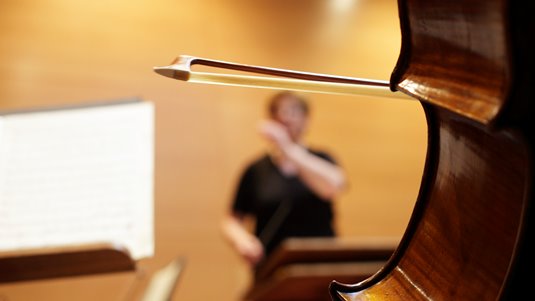 Dirigent i bakgrunden av en cello.