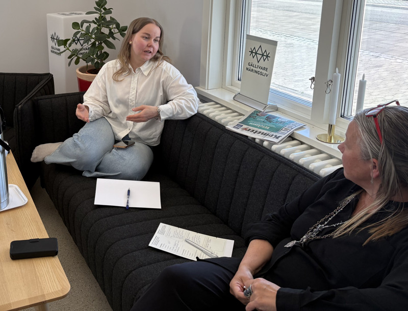 Två kvinnor sitter i en soffa och diskuterar.