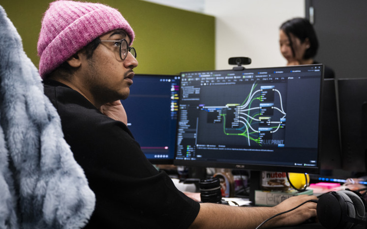 Man i rosa mössa sitter framför en datorskärm