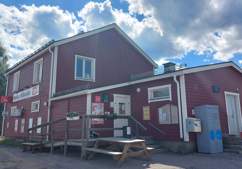 En röd landsbygdsbutik med ett picknickbord framför.