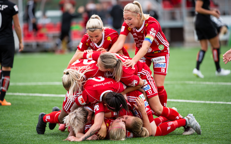 Fotbollstjejer som kramas i en hög