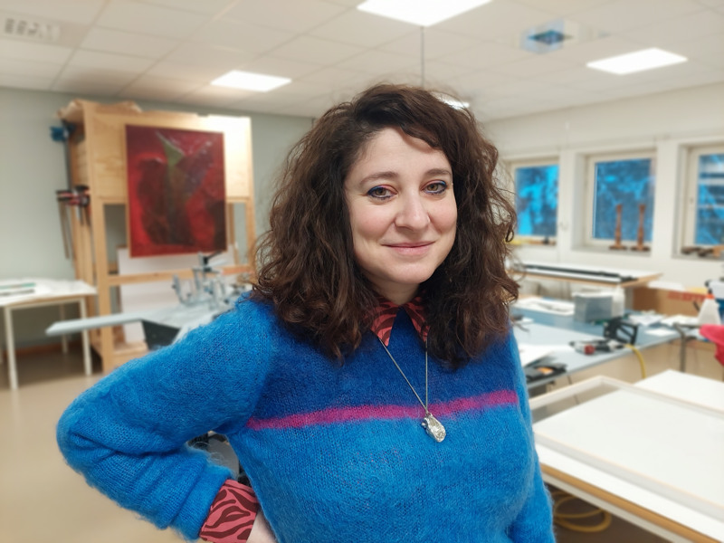 Silvia Colombo står i ett rum omkring konst och ramar 
