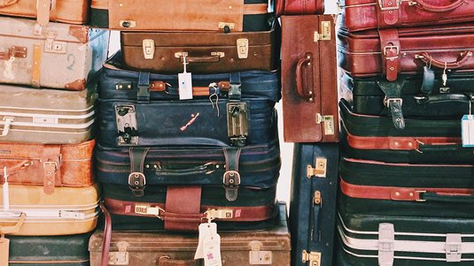 Äldre resväskor i olika färger staplade på varandra.