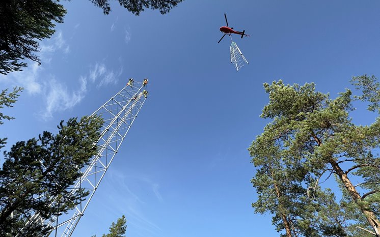 Samhällsmasten på Storbrändön med en helikopter svävande ovanför.