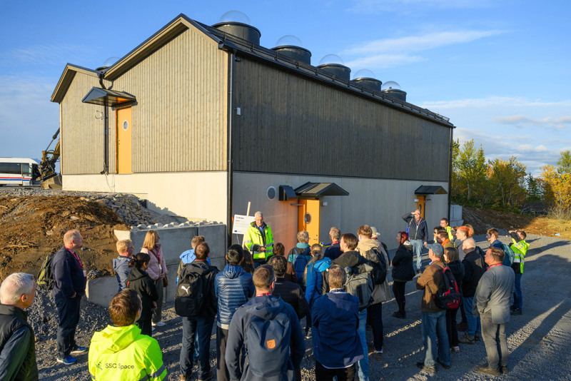 Folksamling vid byggnad.