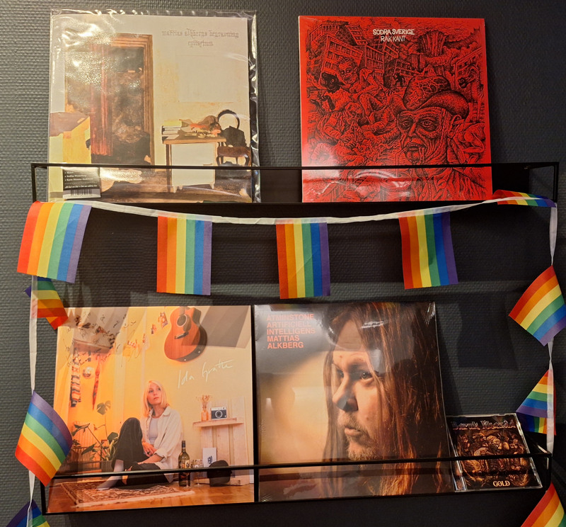 Foto av en hylla på BD Pop med fyra LP-skivor. En girland med Pride-flaggor är draperad på hyllan.