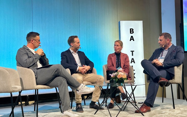 Fyra personer samtalar på en scen, skylt med BA Talks i bakgrunden.