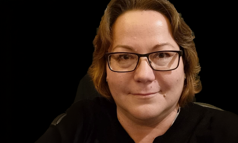 En kvinna med glasögon och svart skjorta.