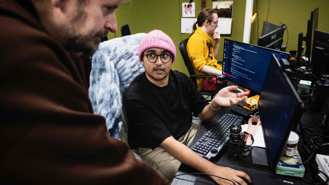 Unga personer sitter vid datorer och arbetar i en kreativ miljö.