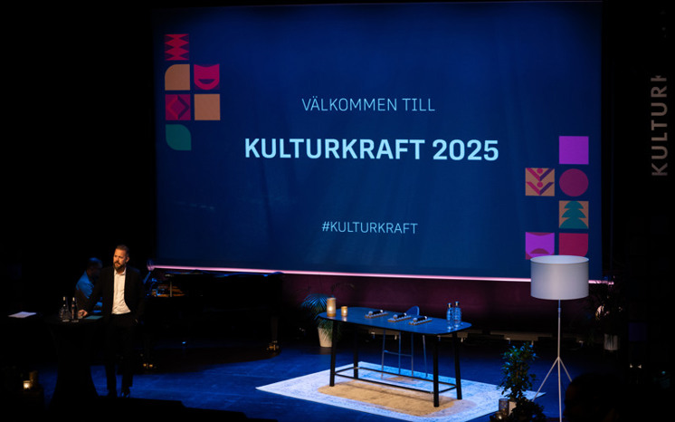 Moderator Anders Rydell hälsar välkommen. Det står "Välkommen till Kulturkraft 2025" på skärmen bakom honom.