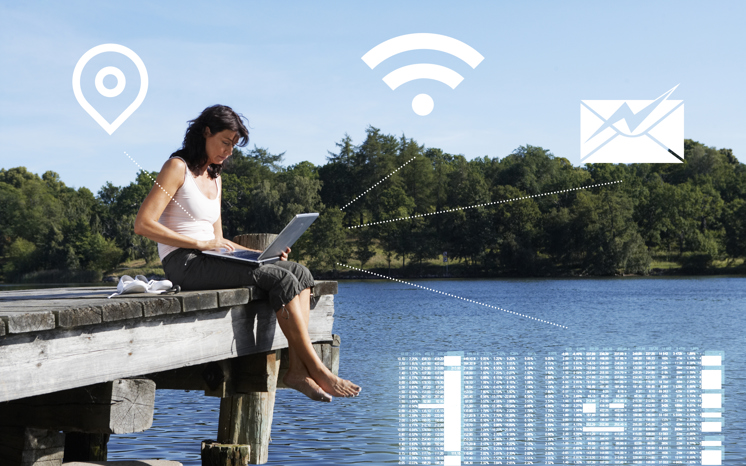 Digitala symboler över kvinna sitter på brygga med laptop. 