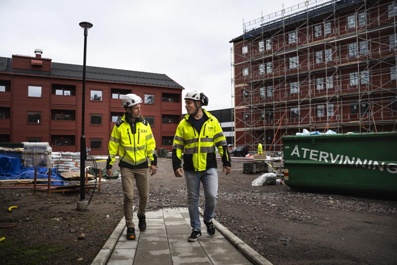 Två män i varselkläder går på en byggarbetsplats.