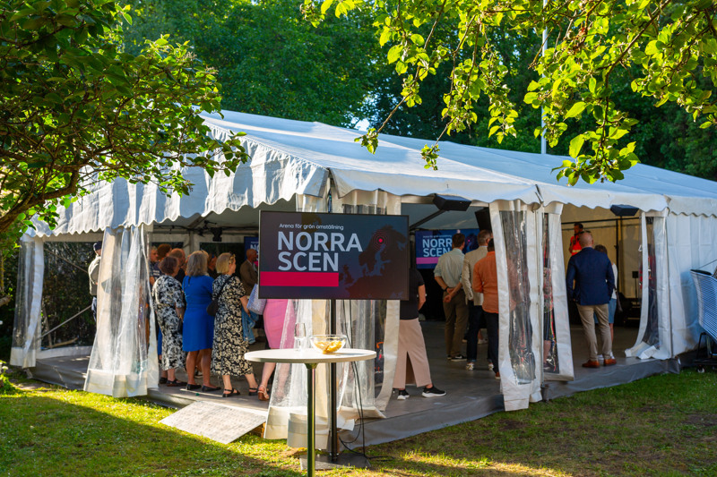 Partytält i en trädgård med människor i, skylt där det står Norra Scen framför.